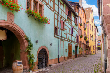 Colorful half-timbered buildings with shops and cafes in the medieval old town of Riquewihr, France, one of France's "most beautiful" villages along the Alsatian Wine Route.
