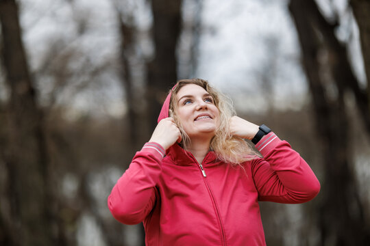 Woman in Jacket Holding Hoodie Over Head After Training .Outdoor