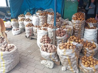 Many white bags of potatoes are sold at the market