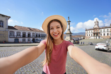 Beautiful traveler girl takes self portrait in Tiradentes Square famous landmark of Ouro Preto,...
