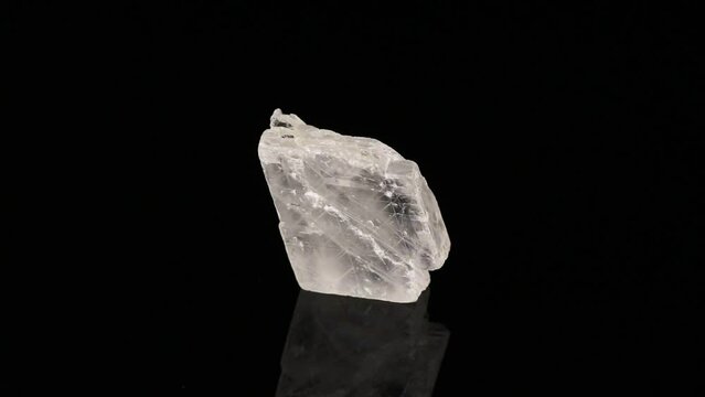 Polished mineral stone iceland spar rotates in a circle on a black background