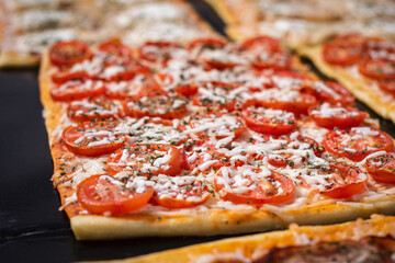 Close up. Portion square pizza with tomatoes and cheese. Spanish street food.