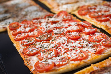 Close up. Portion pizza with tomatoes and cheese on showcase. Barcelona street food.