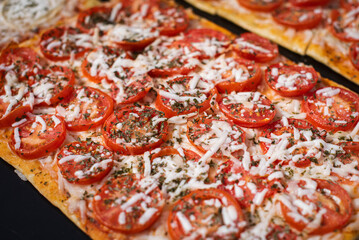 Close up, macro. Portion square pizza with tomatoes and cheese. Spanish street food.