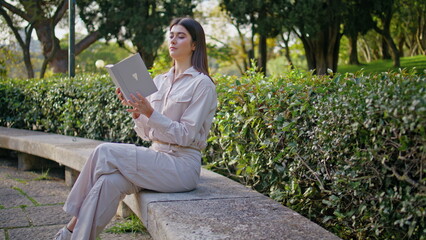 Relaxed girl looking book in green park eating apple. Calm woman enjoy reading