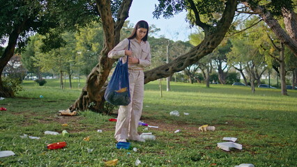 Woman cleaning park grass picking up discarded trash. Girl cleanup nature