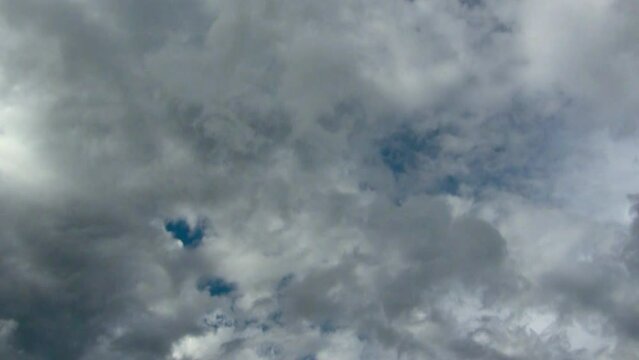 Storm clouds at different altitudes are forming under blue sky and moving in different directions, in time lapse clip.
