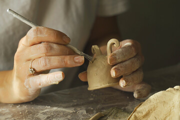 A woman makes a ceramic pot and legs using a tool.