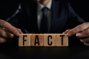 A man's hand shows the word fact on a wooden cube. truth concept