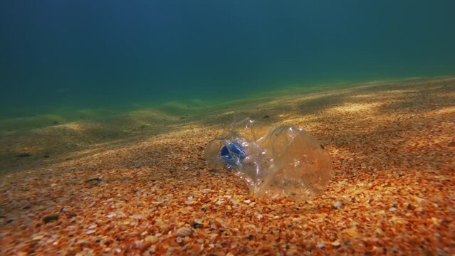 Plastic pollution on the ocean floor. Bottle shaped like trash at the bottom of the sea