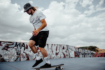 A man in a white shirt and black shorts is skateboarding on a concrete surface