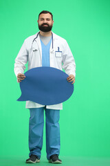 Male doctor, full-length, on a green background, shows a blue comment sign