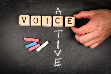 Active voice. Wooden block crossword puzzle and pieces of chalk on a chalkboard background - 793268970