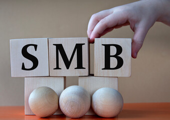 A child's hand places a large cube next to other cubes. SMB acronym concept