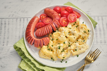 Scrambled eggs, sausage, and tomatoes on a white plate  a hearty dish