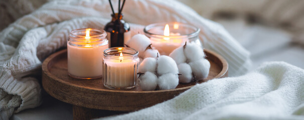 Burning candles, aroma fragrance organic reed diffuser, wooden bamboo tray. Concept of cozy home...