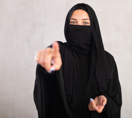 Young muslim lady wearing black traditional niqab talking pointing to side