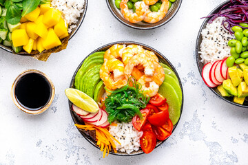 Poke bowls with vegetables and seafood set for balanced diet, white table background, top view