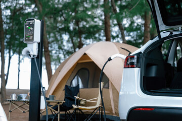 Electric car recharging battery at outdoor EV charging station at natural vacation campsite,...