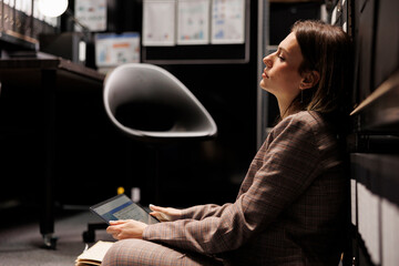 Tired private detective working late at night in arhive room, analyzing crime scene evidence trying...