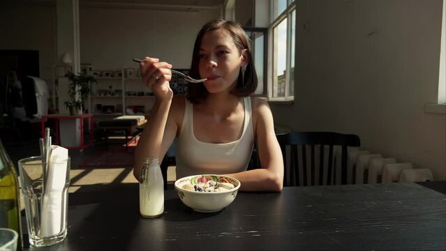 Woman eating trendy breakfast with tiny mini pancakes served blueberry. Heap of baby cereal pancakes with yogurt in cafe
