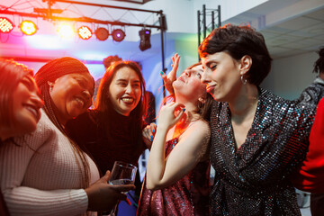 Cheerful smiling women drinking alcohol, hugging and partying together in nightclub. Carefree...