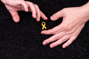 Hands placing a yellow ribbon pin on fabric, the international symbol of advocating for the return...