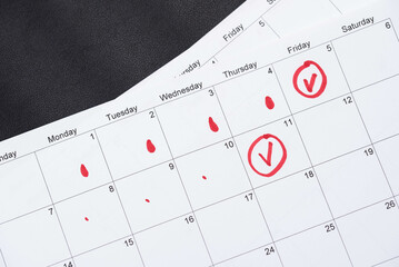 Hand draws red drops on the calendar, then places a red checkmark in a circle - concept of menstrual cycle tracking, ovulation, and pregnancy planning - obrazy, fototapety, plakaty