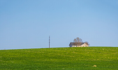 Minimalistic landscape with a farmhouse on the hill. Colorado at the spring