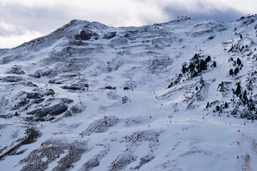 A snowy mountain with a ski slope. The slope is covered in snow and has a few people skiing on it