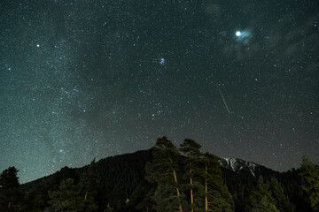 night sky with stars and a meteor above a mountain