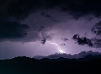 lightning bolt in the sky above the mountains with dark clouds