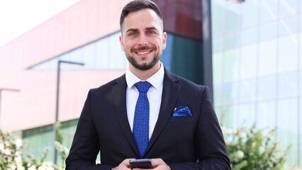 Fototapeta premium Happy young businessman enjoying outdoors and using smartphone