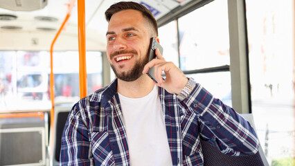 Young man riding in a city bus and talking on mobile phone