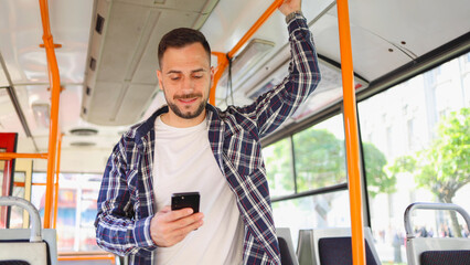 Young man riding in a city bus and using his smartphone