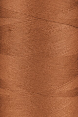 Texture of orange color threads in spool close up, macro. Sewing threads bobbin abstract background, wallpaper, backdrop.