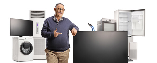Mature man pointing at a flat tv screen and home electric appliances