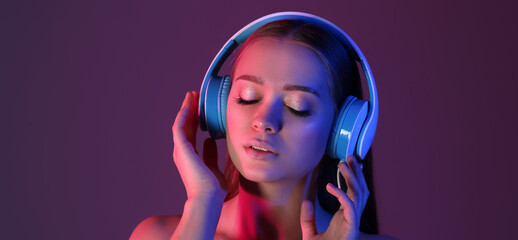 Toned portrait of beautiful young woman listening to music on color background