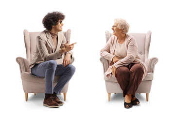 Young man sitting in an armchair and talking to an elderly woman