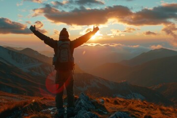 Man with arms raised in celebration on the summit during a picturesque sunset