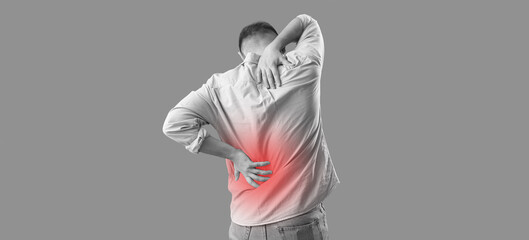 Young man suffering from back pain on green background