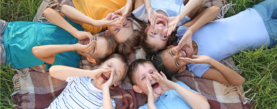 Group of children lying on plaid in park - Powered by Adobe