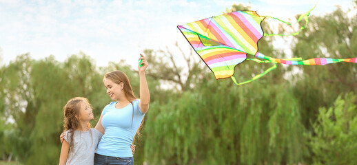 Young woman with little daughter flying kite outdoors