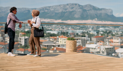 After a day at the office, a business man engages in conversation with his Muslim colleague wearing...
