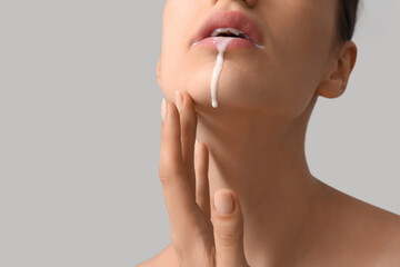Young woman with dripping white liquid on light background, closeup. Sex concept