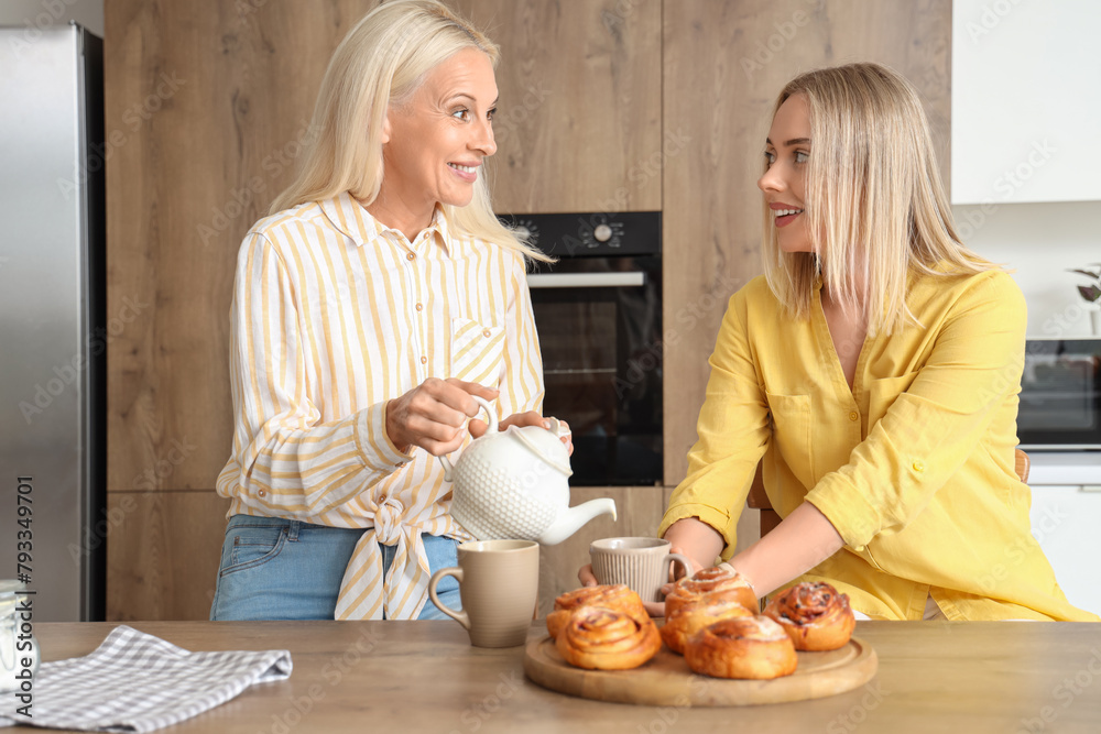 Canvas Prints beautiful young woman and her mother drinking tea with tasty buns in kitchen