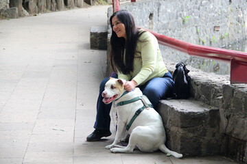 A 40-year-old Latina woman spends time in the park with her emotional support dog who accompanies her to make her feel better about her emotional or psychological difficulties