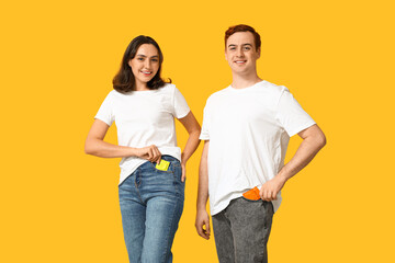 Young couple with condoms on yellow background. Safe sex concept