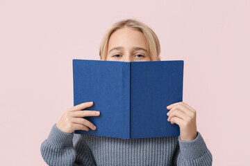 Cute little boy with book on pink background