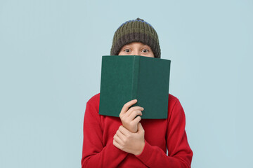 Cute little boy with book on blue background